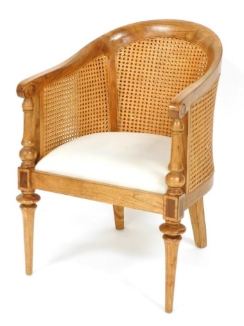 A continental hardwood bergere armchair, with a shaped back, padded seat, on turned tapering legs.