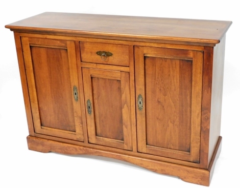 A Continental fruit wood side cabinet, with a frieze drawer above a panelled door flanked by two larger panelled doors on bracket feet, 91cm high, 135cm wide, 46cm deep.