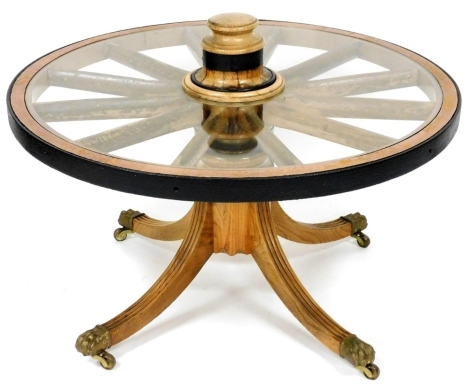 An unusual coffee table, constructed from a 19thC ash cartwheel, on a turned column and reeded splayed legs with brass castors, 100cm diameter.