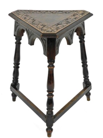 A late 19th/early 20thC carved and ebonised oak triangular occasional table, with a moulded edge, with a shaped apron on turned supports with two stretchers, 68cm high, 57cm wide.