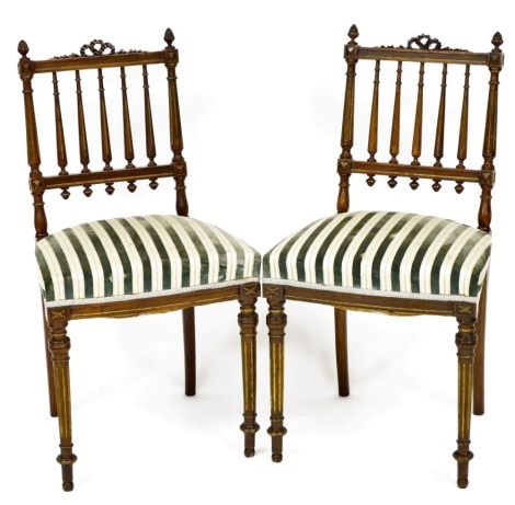 A pair of early 20thC Continental walnut and parcel gilt side chairs, each with a turned rail back, solid seat on turned tapering legs.