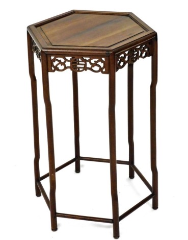 An Oriental hardwood occasional or urn table, the hexagonal top with a moulded edge, above a pierced carved frieze on shaped legs with under tier, 46cm wide.