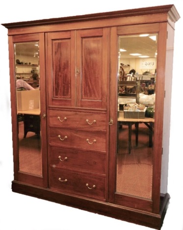 An Edwardian Maple and Co mahogany triple wardrobe compactum, the dentil cornice raised above a boxwood inlay centred by panelled doors and drawers flanked by mirrored sections on a block base, 210cm high, 194cm wide, 47cm deep.