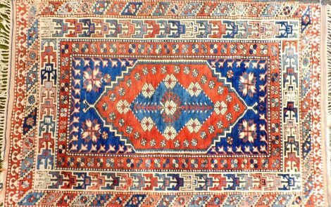 A Persian style rug, with a central pole medallion in navy on a red ground with navy spandrels, each with geometric devices, one wide and two narrow borders, 170cm x 110cm.