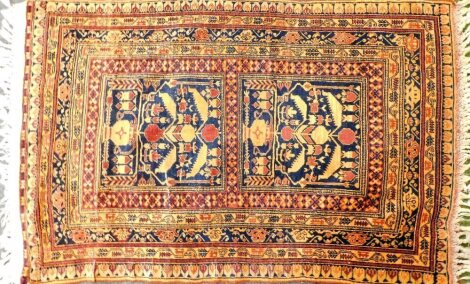 An Eastern carpet, with a design of birds, flowers, etc., in shades of orange on a navy ground with multiple borders, tasseled ends, 147cm x 94cm.