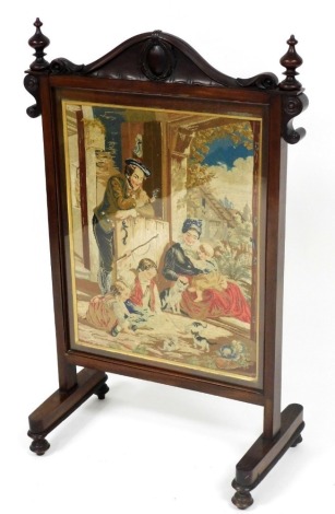 A Victorian mahogany fire screen, the top with a carved crest rail and turned finials, the central inset panel with an embroidery depicting a pastoral scene with family playing with kittens, on rectangular supports terminating on turned feet, 106cm high.