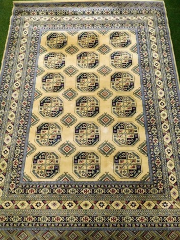 A Persian cream ground rug, decorated with three rows of six geometric and floral medallions, within repeating blue and cream floral and geometric repeating borders.340cm x240cm.