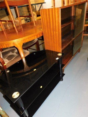 A three tier glass television stand, 82cm wide, and a glaze fronted bookcase, 99cm wide.