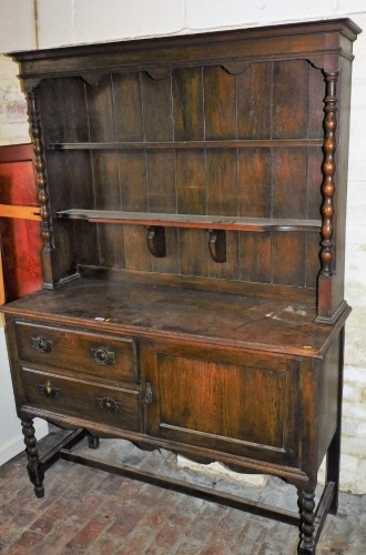 An oak dresser, with plate rack back, on twist column supports with two drawers and single cupboard, on H frame base with partial twist legs, 190cm high.