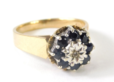 A ladies 9ct gold dress ring, florally claw set with small sapphires centred by a white stone, size N, 4.4g all in.