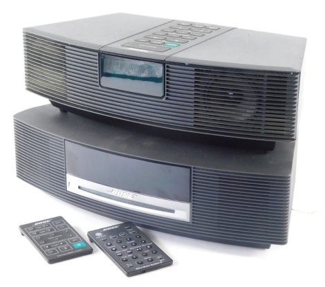 A Bose Wave III music system, no. 055426330980245AE and an AWR1-2W Bose Wave radio, each with wires and remote controls. (2)