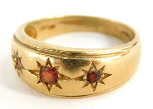 A dress ring, marked 9k, set with three small garnets, size R/S, 5.3g all in.