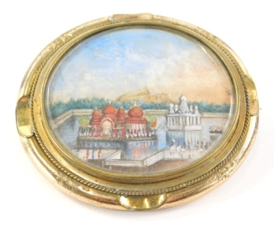 A 19thC Indian brooch, inset with an oval miniature of a temple, and an engraved back, All My Love Eric, 22/4/46, in a yellow coloured metal mount, 6cm wide.