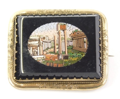 A 19thC Italian micro mosaic brooch, decorated with ruins on a rectangular black onyx backing, in a yellow coloured metal mount, with safety chain and later steel pin back, 22.7g all in, the brooch, 5cm wide, 4cm high.