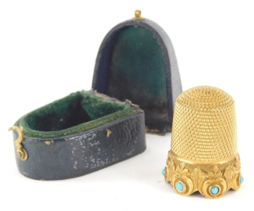 A gilt metal thimble, engine turned and set with turquoise, unmarked, 2cm high, partially cased. (AF)