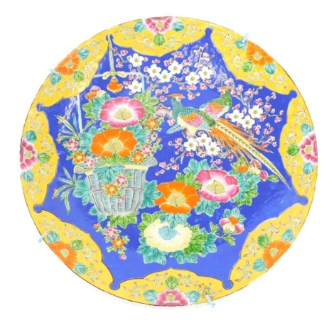 An early 20thC Japanese famille jaune charger, profusely decorated with flowers on a yellow and blue ground, 44cm diameter.