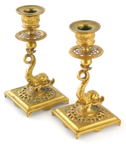 A pair of Regency style gilt metal candlesticks, each with dolphin stems, compressed Neo classical dish holders and square part pierced feet, unsigned, 16cm high.