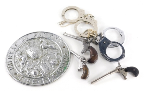 Two pairs of handcuffs, one marked Hatts, a reproduction fire resisting Milner's Patent safe plaque, 20cm diameter, various starting pistols. (a quantity)