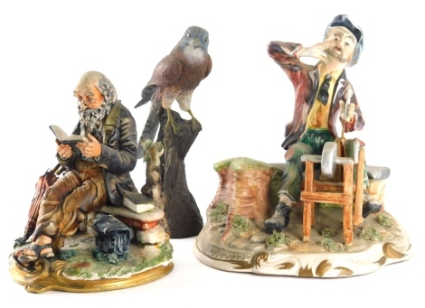 A Capodimonte figure of a tramp sat on bench reading, marked N108 Italy, gilt highlighted base, 28cm high and a further Capodimonte figure group and a figure of a kestrel. (3)