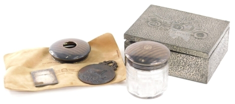 A George V silver and cut glass dressing table jar, with compressed engine turned lid initialled, Birmingham 1923, 7cm high, Greggs medallion, further silver hair pot lid and a hammered box, the lid set with car.