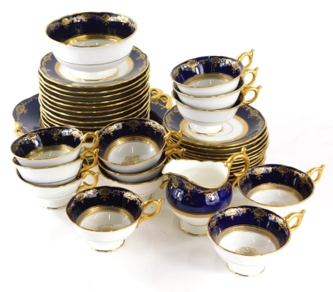 An early 20thC Coalport part tea service, in blue, white and gilt, to include two serving plates, 24cm wide, cups, saucers, side plates, milk jug, part set, etc., decorated with a floral centre on a white ground, part settings for twelve, printed marks be