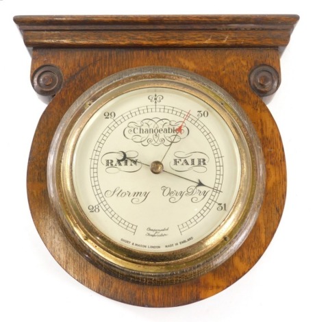 An Edwardian oak wall barometer, in circular case with 15cm diameter dial in brass casing, 28cm high.