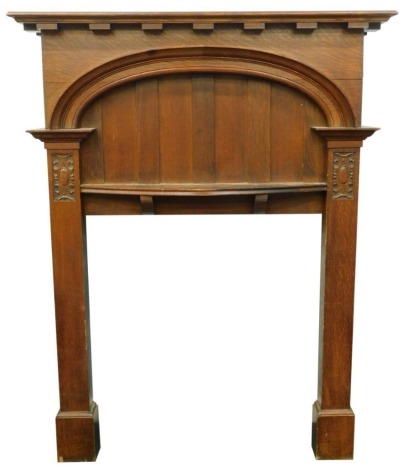 An early 20thC oak Arts and Crafts style fire surround, with moulded bow shaped mantel, a slatted recess, on plain supports each headed by carved cartouches, 184cm high, 143cm wide.