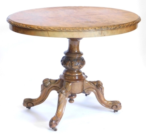 A Victorian walnut loo table, of oval form with quarter veneered top, on heavily carved stem, terminating in quadruple carved legs, with pot castors, 72cm high, 98cm wide, 60cm deep.