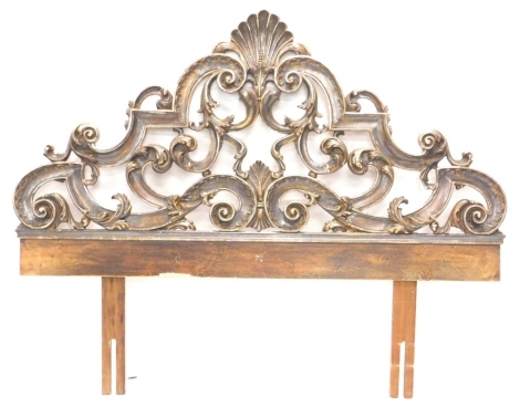 A continental Florentine style silvered and giltwood headboard, decorated with scrolls, leaves, etc., around a central shell, 141cm high, 117cm wide.