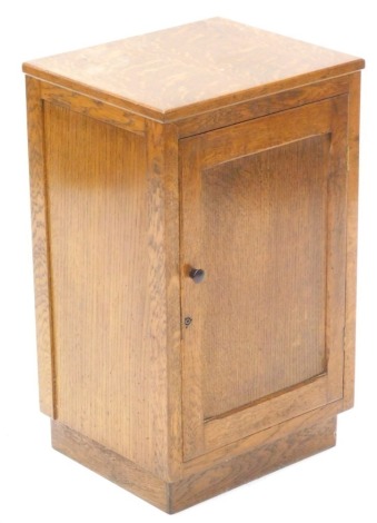 An Art Deco oak pot cupboard, with single panelled door and Bakelite handle on a plinth, 36.5cm wide.