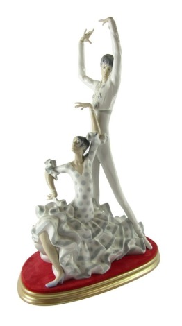 A Lladro porcelain figure group of flamenco dancers, depicting a man, and woman in a polka dot dress, impressed and printed marks, on a gold finish and velvet cushion base, 51cm high.