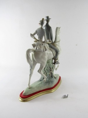 A Lladro porcelain figure group of a lady and gentleman riding on horseback, the gentleman in riding suit, with lady in a polka dot dress, mounted on a white horse, printed and impressed marks, on a gold and red plinth, 48cm high, 37cm wide. (AF) - 4