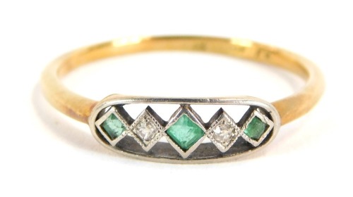 A 18ct gold Art Deco dress ring, with oval panel set with three spandrels each set with square cut stone, comprising three emeralds and two diamonds, in a platinum setting, on a yellow metal band, size S, 2.4g all in.