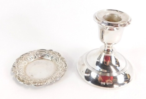 Two items of silver ware, comprising a Victorian silver pin dish with an embossed foliate scroll decoration, Glasgow 1892, together with a George V silver dwarf candlestick, London 1912, on weighted base, 5 3/4oz gross.