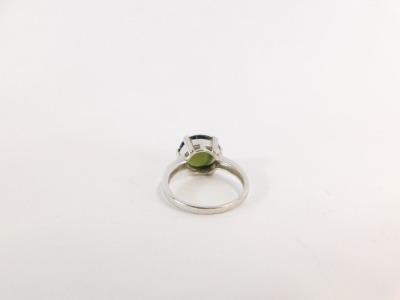 A 9ct white gold dress ring, with oval set green central stone, in a six claw setting on a raised basket, size P, 4.6g all in, boxed. - 2