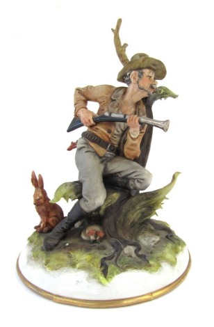 A Capo di Monte figure group, by Tosca, of a hunter with blunderbuss and hare, painted with a gilt border, 25cm high.