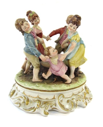 A Capo di Monte porcelain figure group, by Merli, modelled with a family dancing around a tree stump, on a rococo scroll base, 20cm high.