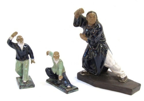 Three Mudmen figures of Oriental figures in pose, each with a blue and green glazed finish, the largest 23cm high.