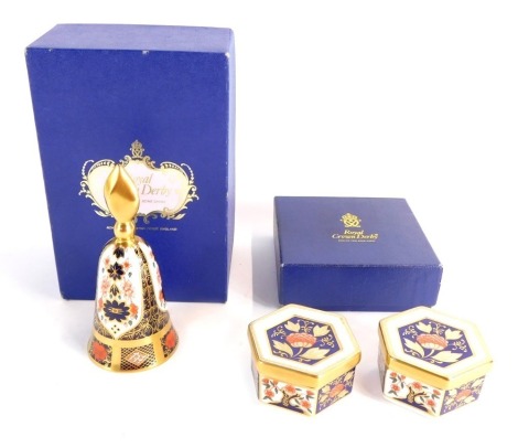 A Royal Crown Derby Imari porcelain candle snuffer, of bell form, together with two hexagonal trinket boxes and covers, printed marks, 2 boxed. (3)