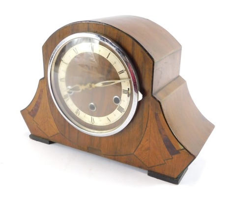 A 1950's Art Deco Revival walnut mantel clock, the shaped fan clock with a silver chapter ring bearing Roman numerals and chrome face, eight day chimeing movement, 22cm high, 32cm wide, 12cm deep.