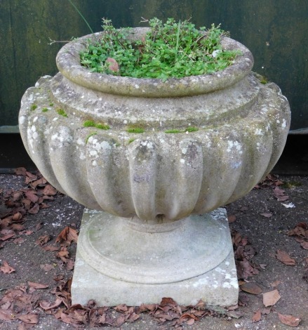 A cast concrete urn planter, the urn on a square set base, 53cm high, 60cm wide.