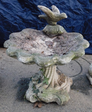 A cast concrete bird bath, shaped as a conch shell with dove, on moulded base, 55cm high, 50cm wide.