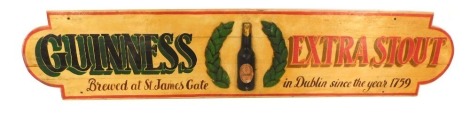 A Guinness Extra Stout wooden pub advertising, with raised relief Guinness bottle in crest, marked James Gate Dublin, since the year 1759, on a cream background with red border, 150cm wide.