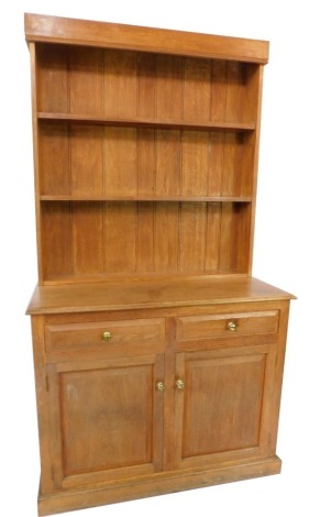 A light oak kitchen dresser, the top having three shelves with plain moulded cornice, the base with two drawers and two doors, each with brass knop handles, on plinth feet, 203cm high, 110cm wide, 50cm deep.