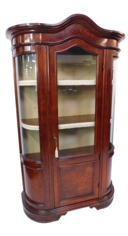 A Continental cherrywood display cabinet, the moulded cornice above arched and glazed panelled doors, on concave sides with two fitted shelves, with cream frill borderings, with enclosed cupboard base, 190cm high, 103cm wide, 54cm deep.