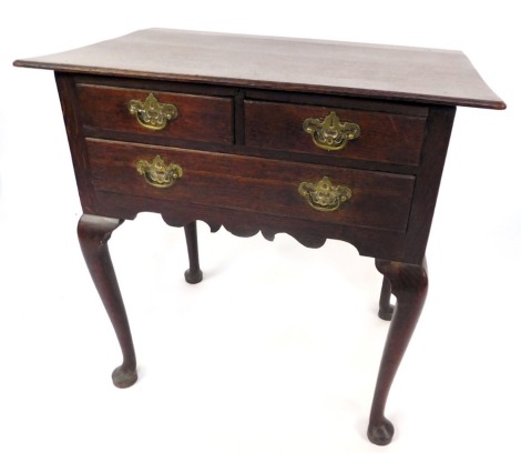 A 19thC oak lowboy, with canted corners above arrangement of two short and one long drawer, with brass drop handles, above a shaped apron on cabriole legs and pad feet, 74cm high, 75cm wide, 49cm deep.