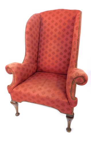 A late 19thC wingback armchair, with studded detailing on a red pattern fabric with out splayed arms on mahogany pad feet, 122cm high, 90cm wide, 56cm deep.