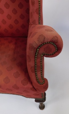 A late 19thC wingback armchair, with studded detailing on a red pattern fabric with out splayed arms on mahogany pad feet, 122cm high, 90cm wide, 56cm deep. - 2