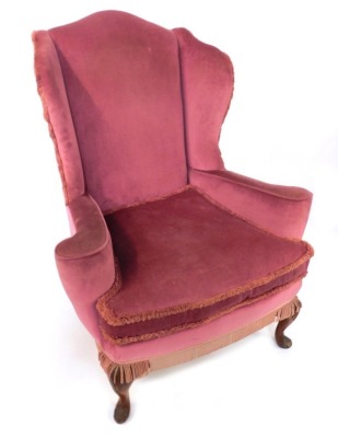 An early 20thC wingback armchair, in George III style, pink draylon upholstery with tassle ends, 105cm high, 89cm wide, 70cm deep.