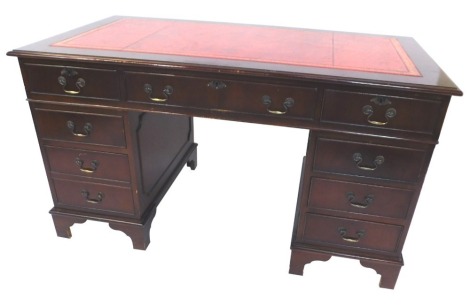 A mahogany pedestal desk, the top with red leather inlay, above central drawer and four small side drawers, on bracket feet, 76cm high, 137cm wide, 76cm deep.